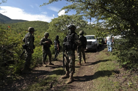 Image: Soldiers guard an area where a mass grave was found, in Colonia las Parotas on the outskirts of Iguala, in Guerrero