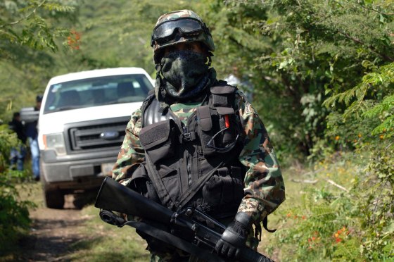 Image: A Mexican navy marine guards the road that leads to the site where an alleged clandestine mass grave was found