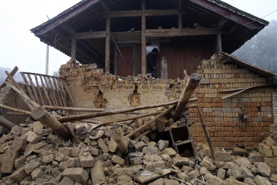 Image: A man carrying a bag walks past the ruins of a damaged house after an earthquake hit Yongping township of Jinggu county
