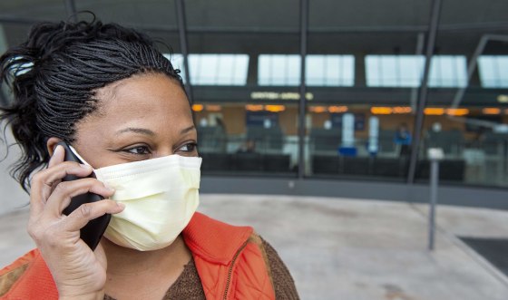 Image: A nurse arriving from Dayton, Ohio, and concerned about Ebola reports, wears a precautionary surgical mask at Dulles International Airport