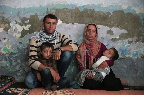 Syrian Kurdish fighter Delkhwaz Sheikh Ahmad, 22, sits with his wife Siham, 23, and their two sons, Dilyar, left, 3 and Ibrahim, 2, right, at his brother's house in Suruc, on the Turkey-Syria border, as he prepares to leave for Kobani, Syria, to rejoin the fighting, Friday, Oct. 17, 2014.