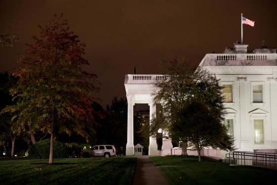 Image: A group of Secret Service police gather on the North Lawn as a member of the Secret Service Counter Assault team surveys from the White House rooftop
