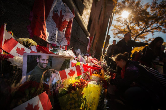 Image: A photograph of Cpl. Nathan Cirillo is displayed at a makeshift memorial in honour of his death, as people pay their respects in Hamilton