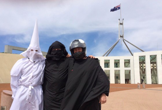 Image: Three men wearing a Ku Klux Klan hood, a niqab and a motorcycle helmet pose for a photo outside Australia's Parliament House in Canberra
