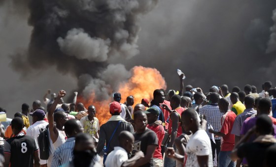 Image: People stand in front of smoke rising from the Burkina Faso's parliament