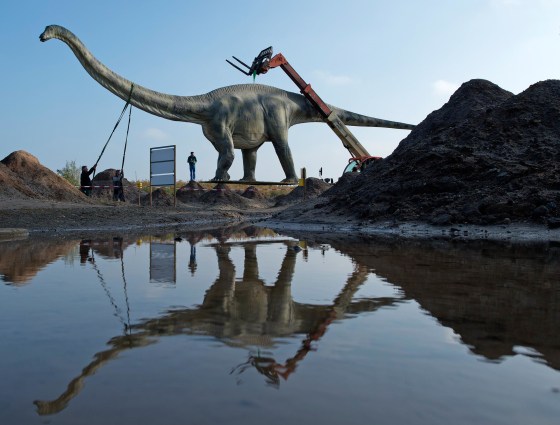 Image: Workers transport a model of a dinosaur