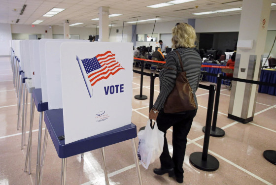 A woman walks past voting booths at the Cuyahoga County Board of Elections in Cleveland, Tuesday, Oct. 7, 2014. Early voting began in Ohio after the U.S. Supreme Court stepped into a dispute over the schedule, pushing the start date back a week in the swing state. (AP Photo/Mark Duncan)