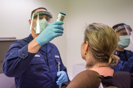 Image: Coast Guard Corpsman checks the temperature of a traveler at Washington Dulles International Airport
