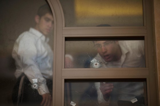 Image: Two youths look at bullet holes and forensic evidence inside a synagogue after an attack in Jerusalem