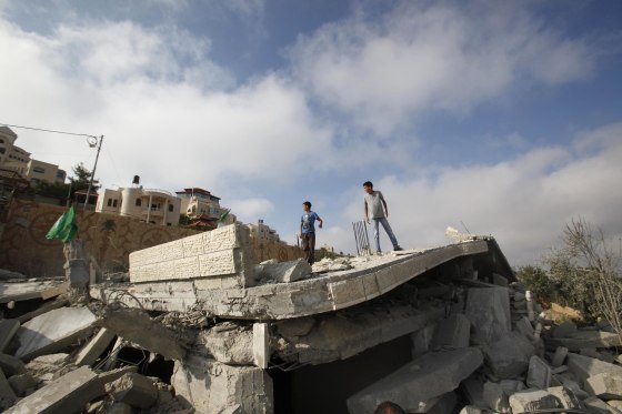 Palestinians stand on the remnants of the house of Hussam Kawasma, one of three Palestinians identified by Israel as suspects in the killing of three Israeli teenagers, after it was demolished by the Israeli army in the West Bank city of Hebron, on Aug. 18.