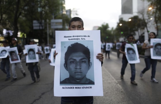 Image: A demonstrator carries a photograph of Mora Venancio, one of the 43 missing trainee teachers, during a march in support of the students in Mexico City