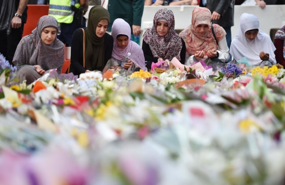 Image: Young Muslim women lay flowers at a makeshift memorial