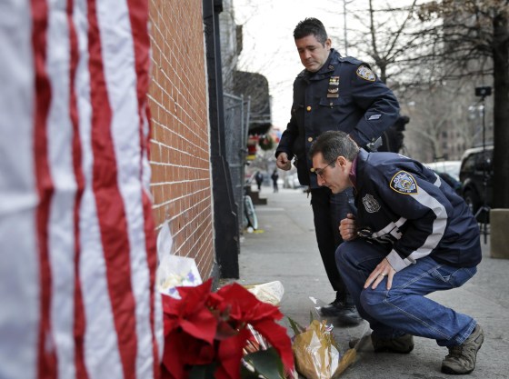 Image: Police officers leave candles at an impromptu memorial near the site where two New York City police officers were killed
