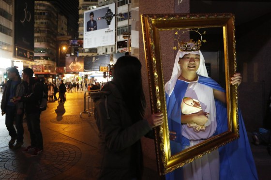 A man dressed as the Virgin Mary with baby Jesus poses for photographs during the early hours of Christmas Day celebrations in the Causeway Bay shopping district in Hong Kong on Dec. 25.