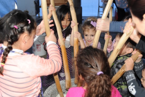 Children begin to break apart rice with sticks at Koda Farms Mochitsuki
