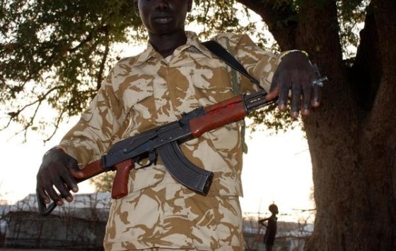 "David", 15, stands holding an assault rifle on January 27, two days before his release from the SSDA Cobra Faction armed group, in Jonglei State, South Sudan.