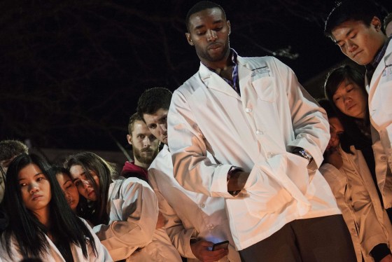 Image: Dentistry students and others huddle together during a vigil