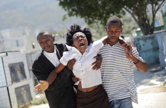 Image: A woman reacts as others help her walk at the cemetery before the funeral for the victims of a Carnival stampede, in Port-au-Prince