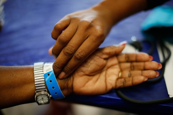 Image: Woman has her pulse taken at Care Harbor LA free medical clinic in Los Angeles