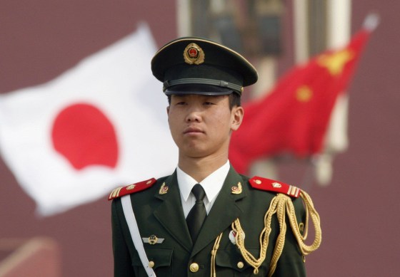 A paramilitary policeman stands guard in front of a Chinese and a Japanese flag at Tiananmen Square in Beijing in this April 29, 2009 file photo. China will welcome all national leaders to a military parade marking the 70th anniversary of the end of World War Two, the foreign minister said on March 8, 2015, the strongest sign yet that it could invite wartime enemy Japan. REUTERS/Christina Hu/Files (CHINA - Tags: ANNIVERSARY POLITICS CONFLICT)
