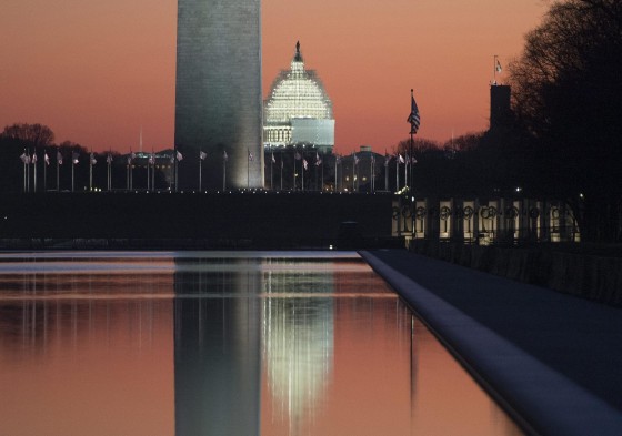 The sun begins to rise on the last day of the year, with the base of the Washington Monument and US Capitol Building reflected in the Lincoln Memorial Reflecting Pool, in Washington DC.