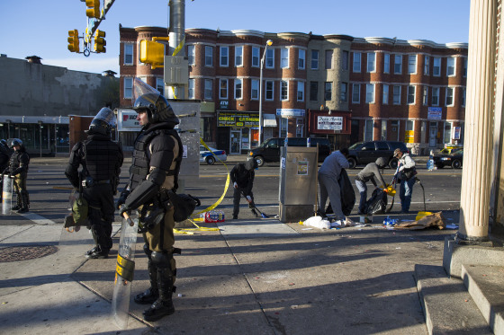Maryland state troopers stand guard, Tuesday, as residents clean up after an evening of riots following the funeral of Freddie Gray on Monday, in Baltimore.