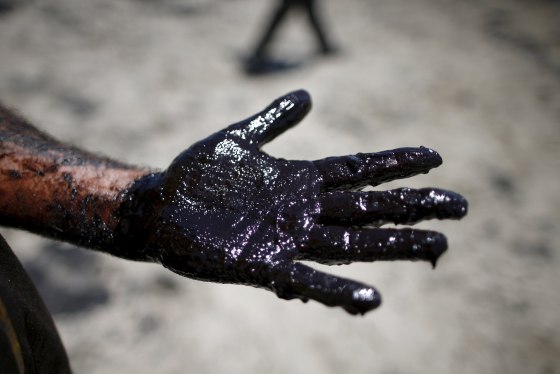 Image: Volunteers carry buckets of oil from an oil slick along the coast of Refugio State Beach in Goleta