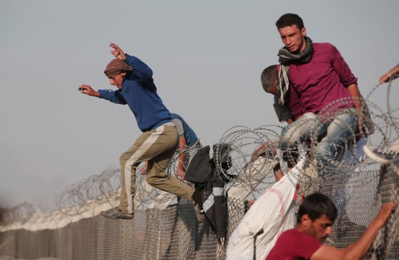 Image: Syrian refugees jump over the border fence from Syria to Turkey