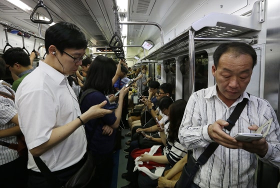 Image: Passengers use their smartphones on a subway train in Seoul, South Korea.