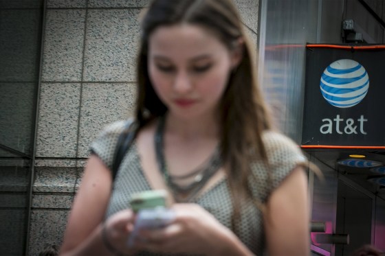 Image: A woman uses her phone outside the AT&T store in New York's Times Square