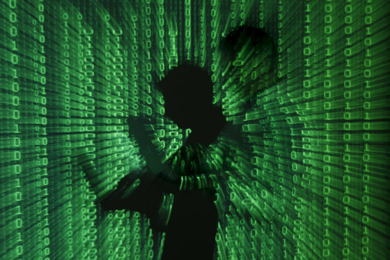 Image: Projection of binary code on man holding a laptop computer