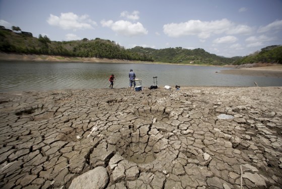 Image: A man and a boy try to fish while standing on the dry shores of the almost empty La Plata reservoir in Toa Alta, Puerto Rico