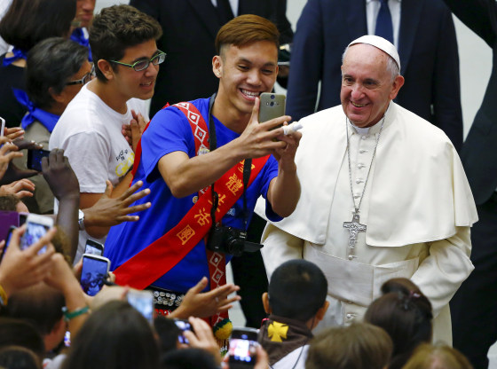 Image: Pope Francis poses for a selfie during a special audience with members of \"Eucharist Youth Movement\" in Paul VI hall at the Vatican