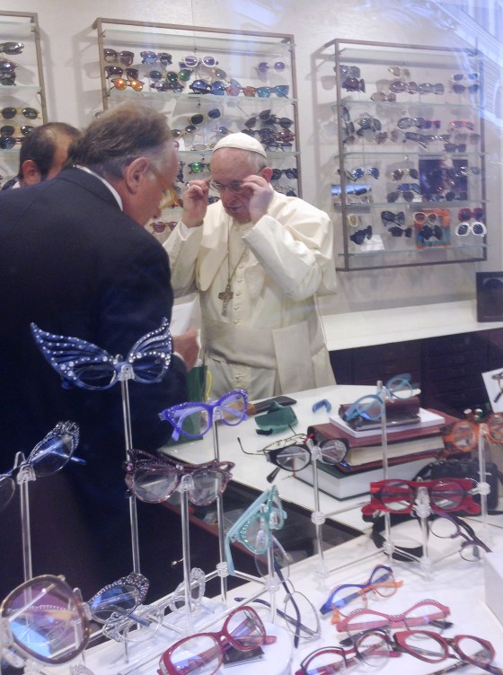Image: Pope Francis tries on a pair of glasses in an optical store in downtown Rome