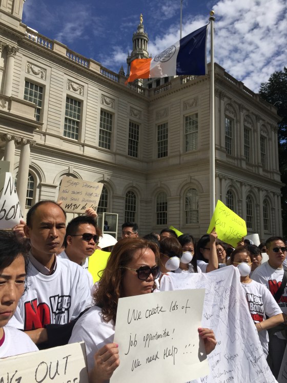 Demonstrators hold up signs protesting provisions of New York State’s nail salon law, including a requirement that salon owners with two-or-more full-time employees purchase wage bonds before Oct. 6.