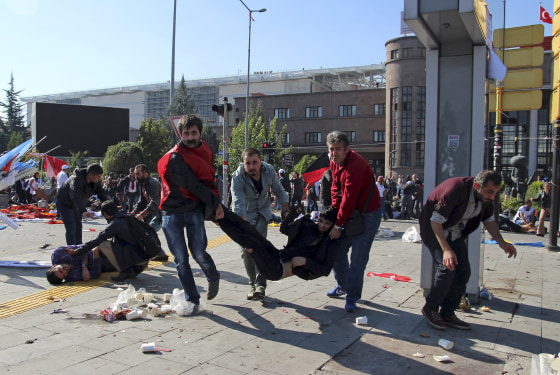 Image: People carry an injured man after an explosion during a peace march in Ankara