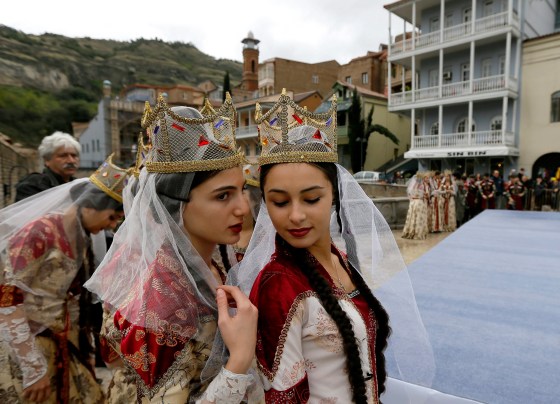 Image: Young Georgian musicians wearing traditional outfits chat during 'Tbilisoba' celebrations