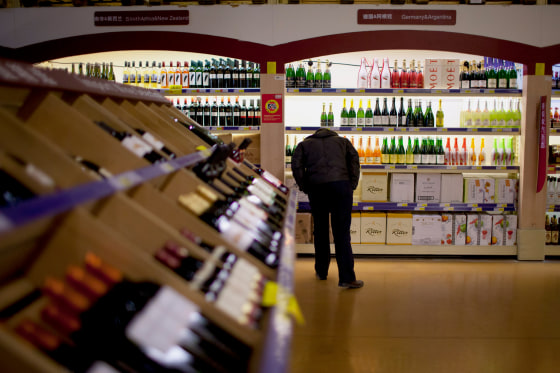 Image: a Chinese man checks out the imported wine in a supermarket in Beijing
