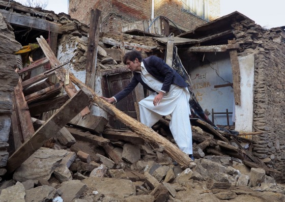 IMAGE: A boy examines a house damaged by massive earthquake