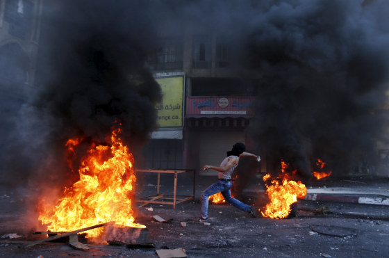 Image: Palestinian protester hurl stones at Israeli troops during clashes in the West Bank city of Hebron