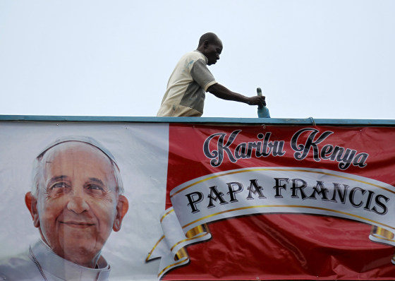 Image: A volunteer paints the wall near a banner of Pope Francis at at the University of Nairobi grounds ahead of the Papal Mass in Kenya's capital Nairobi
