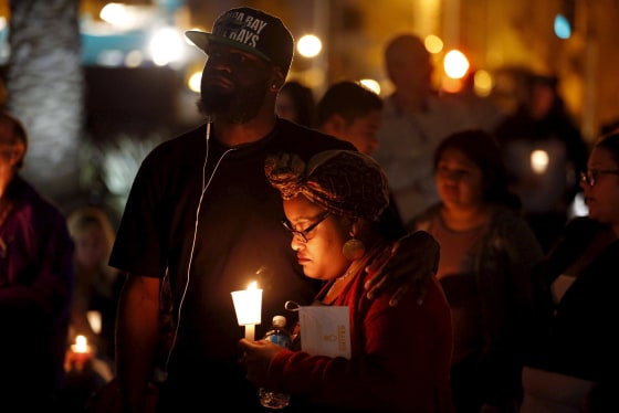 Image: Woman holds a candle during a vigil for San Bernardino County employees after last week's shooting in San Bernardino, California