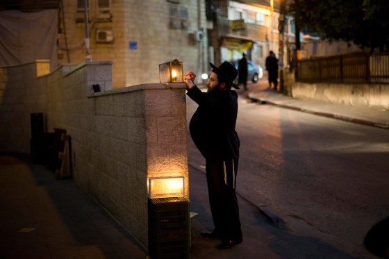 Image: An Ultra-Orthodox Jewish man lights a Hanukkah candle outside his house during the Jewish holiday of Hanukkah