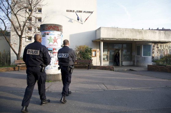 Police stand in front of the nursery school where a hooded man attacked a teacher with a knife near Paris, Monday.
