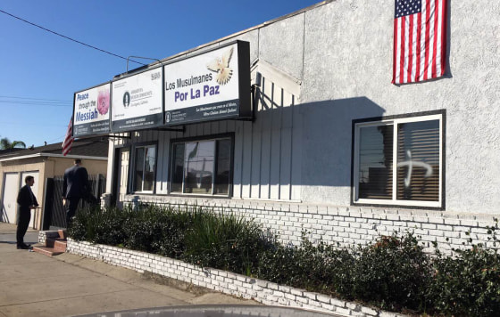 This photo provided by the Ahmadiyya Muslim Community muslimsforpeace.org shows crosses in spray paint vandalizing windows at the Ahmadiyya Muslim Community Baitus-Salaam Mosque in Hawthorne, Calif., Sunday, Dec. 13, 2015. 