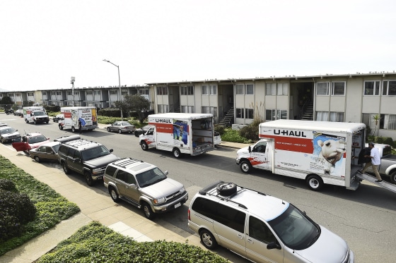 Image: Moving trucks line a street as residents evacuate from an apartment complex which in danger of collapsing due to El Nino storm erosion in Pacifica