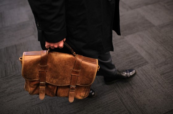 Image: A job seeker carries a worn briefcase