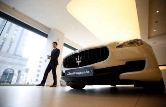 A car dealer walks past a Maserati Quattroporte car at a its dealership in Seoul