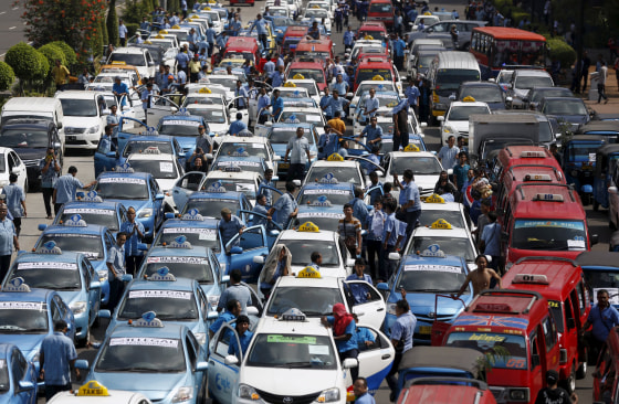 Image: Taxis taking part in a protest rally to demand the government prohibits ride-hailing apps are seen stopped on a main road in Jakarta