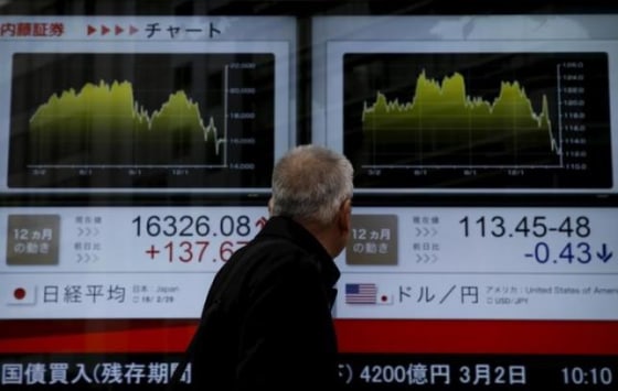 A man looks at an electronic board outside a brokerage in Tokyo